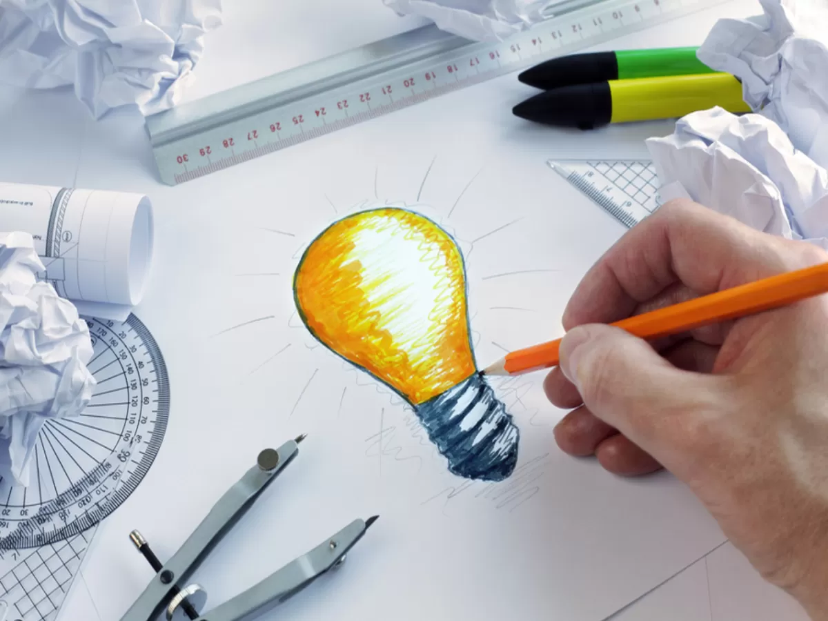 Designer drawing a light bulb, concept for brainstorming and ins